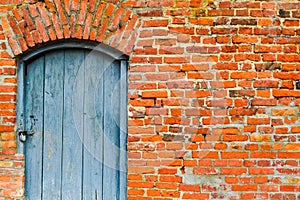 The texture of the old ancient medieval antique solid wooden thick door against the background of a stone wall of red brick