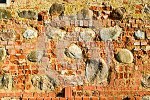 The texture of the old ancient medieval antique stone hard peeling cracked brick wall of rectangular red clay bricks and large