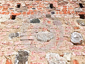 The texture of the old ancient medieval antique stone hard peeling cracked brick wall of rectangular red clay bricks large stones