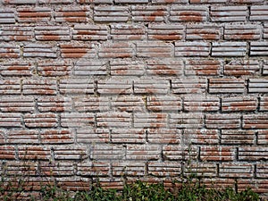 Texture of old brick wall with grass underneath as a background for interior, exterior decoration and design.