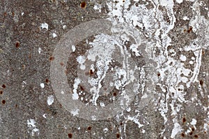 Texture of an old concrete wall with loose plaster and drops of white paint