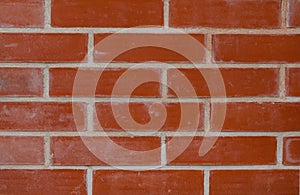 Texture of an old exterior wall surface made of red bricks. Bricks are aged and weathered. Cement mortar between rows