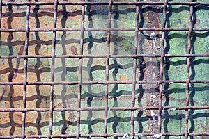 Texture from an old gray iron grate on a green metal wall