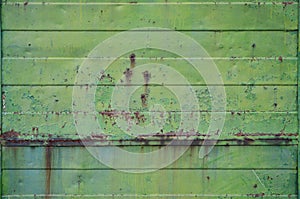 Texture of an old green metal wall with significant damage from exposure to unfavorable weather conditions and dampnes