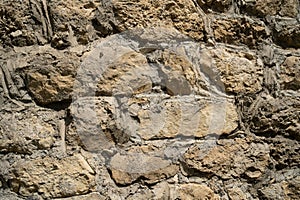 Texture of old stones of various forms with seams. Close up of shabby masonry. Stone wall from uneven different ancient