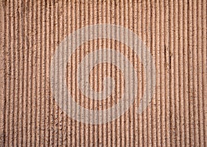 Texture of old wall covered with brown stucco with vertical rel