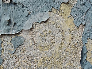 A layer of peeling old blue paint on the relief surface of a concrete cement wallTexture of old white cracked paint on blue concre