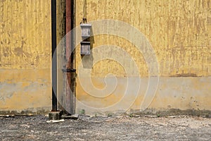 Texture of old yellow vintage wall of industrial factory with rusted iron pole and electric cable