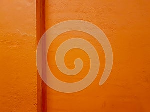 Texture of a painted orange concrete wall with a corner ledge.