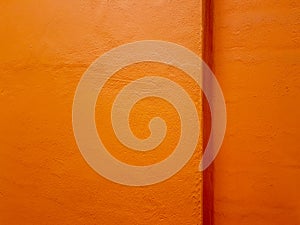 Texture of a painted orange concrete wall with a corner ledge.