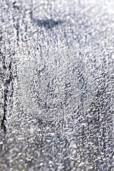 Texture and pattern of white ice and snow crystals on wooden surface close up in bright sunlight