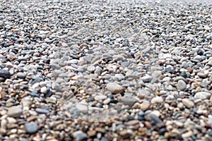 The texture of the pebbly beach. Background of small pebbles on the beach. Blurry background. A picture with an open aperture