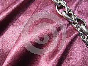 Texture of pink silk with a metal chain element.