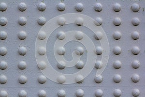 Texture of rivets massive metal construction. Attachment of the metal part of the bridge white painted. Array of convex white