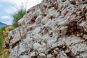 Texture of the rock. Large rocks exfoliate from the rock. The roots of the tree hang down