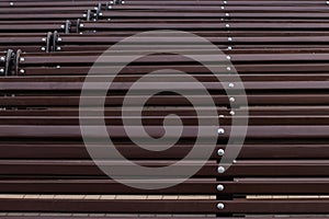 Texture: rows of wooden benches. Dark brown shades. Urban environment background. Photo