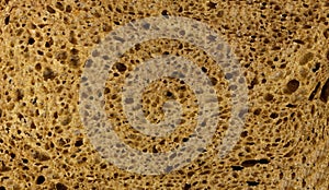 Texture of rye bread. A dark brown piece of bread. Close up