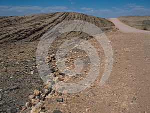 Texture of sandy road trip through dried dusty rock mountain landscape ground of Namib desert background with splitting stone