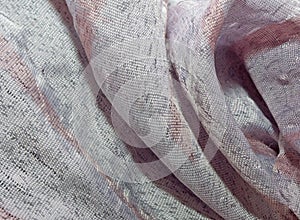 The texture of silk fabric gathered in folds of gray-pink color. Textiles with a metallic sheen.