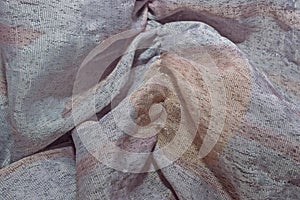 The texture of silk fabric gathered in folds of gray-pink color. Textiles with a metallic sheen.