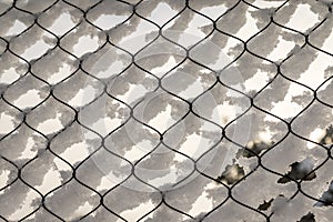 Texture of snow on the fencing net. Plastic mesh covered with snow in winter.