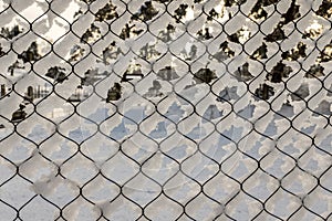 Texture of snow on the fencing net. Plastic mesh covered with snow in winter.