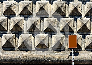 Texture of a stone brick wall in sunlight, close-up with metal plate.