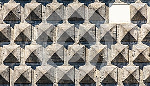 Texture of a stone brick wall in sunlight, close-up with white marble epigraph.