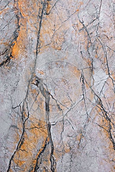 The texture of a stone marble slab with a pink-yellow tint with cracks and streaks