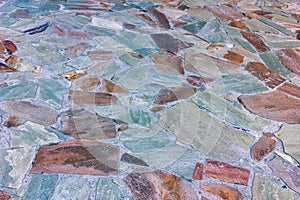 The texture of the stone pavement with grass between the stones close-up.