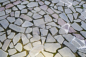 The texture of the stone road, pavement, walls of large gray old medieval round strong stones, cobblestones. The background