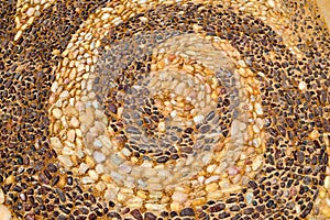 The texture of the stone wall, the road from small round and oval stones with abstracted lines of spiral patterns with sandy