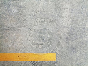 Texture surface of grey concrete road with scratches, indents and chipped with yellow lane divider line with copy space.