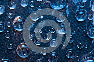 Texture. Transparent raindrops are located on the blue cloth background.