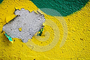 Texture of a two-color yellow and green old shabby concrete wall with bulbous peeling varicoloured paint, pits and patterns