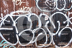 Old wood brown door with black and white graffiti.