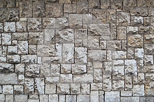 Texture of the wall made of stone blocks of different sizes and light gray color