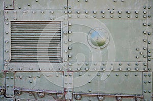 The texture of the wall of the tank, made of metal and reinforced with a multitude of bolts and rivets. Images of the covering of