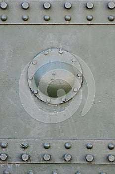 The texture of the wall of the tank, made of metal and reinforced with a multitude of bolts and rivets. Images of the covering of