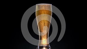 Texture of water drops on the bottle of beer. Rotation glass with beer in 4k shot