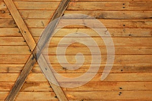 The texture of weathered wooden wall. Texture of an old fence of horizontal orange wooden planks with cross-board