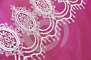 Texture of white decorative lace fabric with floral ornament on pink background
