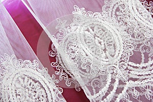 Texture of white decorative lace fabric with floral ornament on pink background