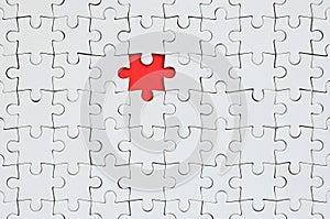 The texture of a white jigsaw puzzle in an assembled state with one missing element forming a red space