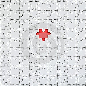 The texture of a white jigsaw puzzle in an assembled state with one missing element forming a red space