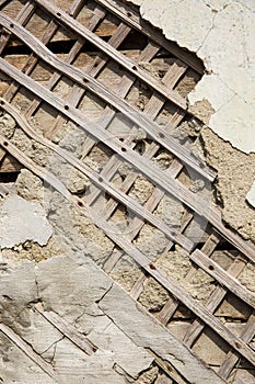 Texture of wooden planks and dry clay on the wall. The old plaster is crumbling.