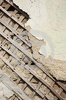 Texture of wooden planks and dry clay on the wall. The old plaster is crumbling.