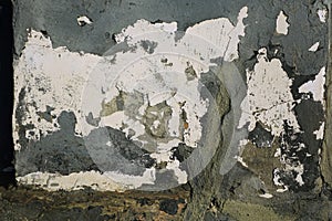 Textured aged wall with layered coating of whitÑƒ paint and grayish plaster with cracks