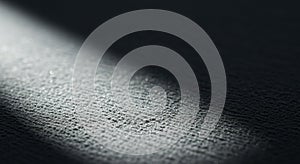 A textured dark surface is partially illuminated by a diagonal beam of light. The