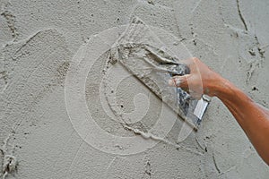 Textured detail of plaster mortar while a worker plastering cement wall at construction site